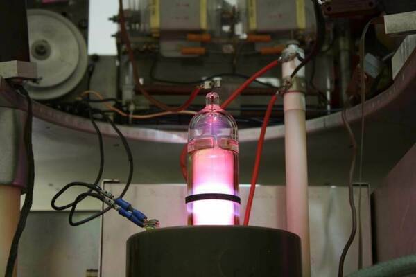 Accelerator at University of Kentucky glows with bright pink light, connected to wires and other components.